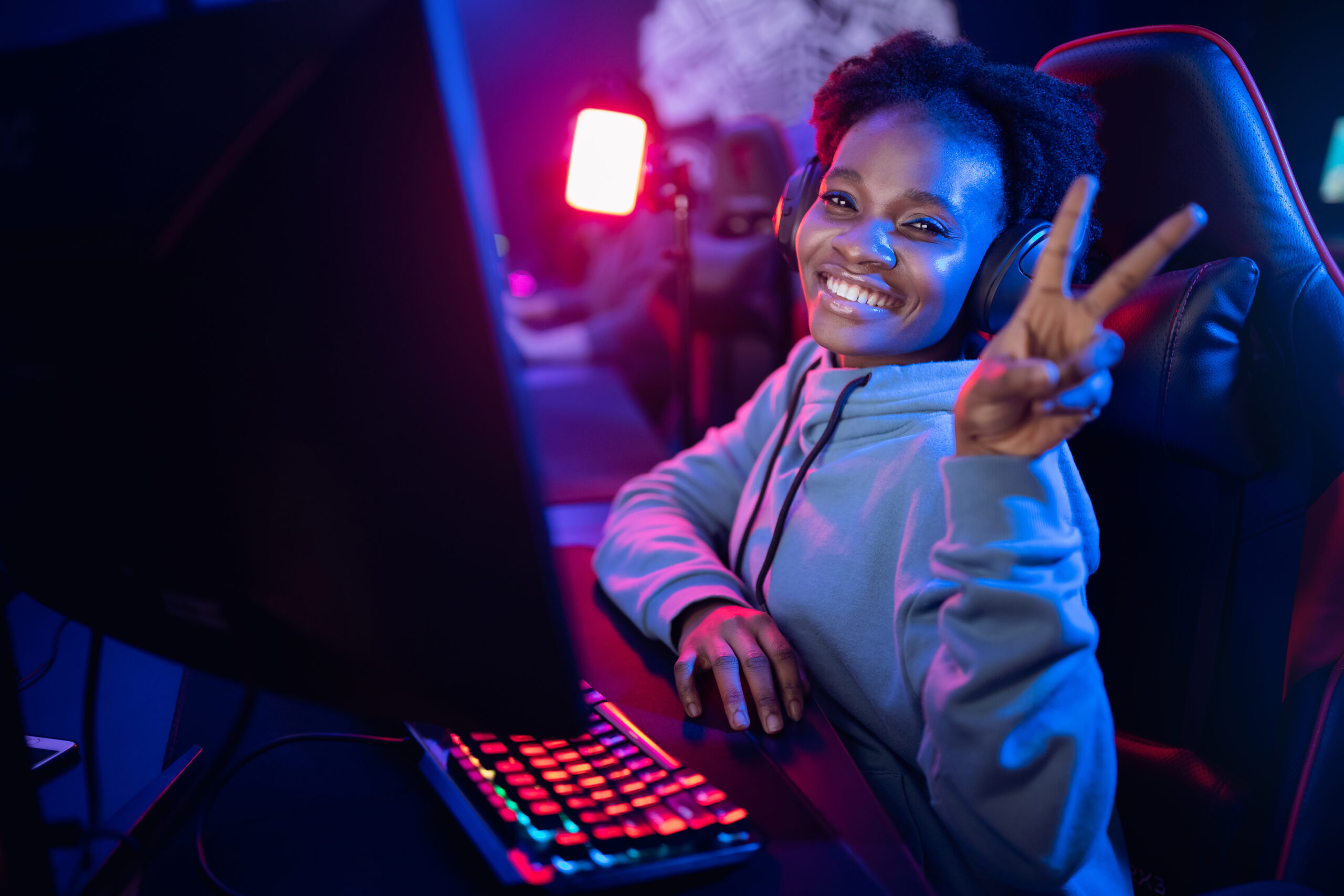 Happy Streamer African young woman professional cyber gamer online video games computer, dark color